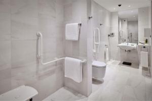 a white bathroom with a toilet and a sink at Parklane, a Luxury Collection Resort & Spa, Limassol in Limassol