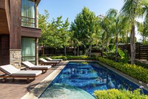 a swimming pool with lounge chairs and a house at Parklane, a Luxury Collection Resort & Spa, Limassol in Limassol