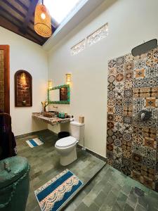 Uluwatu Lumbung Cottages في أُلُواتو: حمام مع مرحاض ومغسلة