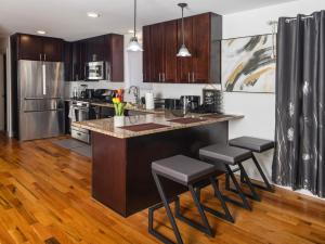 a kitchen with wooden floors and a counter with stools at Stylish & family friendly 3 Bedroom - 8 mins to EWR in Elizabeth