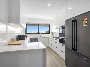 a kitchen with white cabinets and a stainless steel refrigerator at Picture-Perfect Mornington Getaway in Mornington