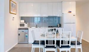 メルボルンにあるMelbourne One 2B2B1C Apartment by GoodLiveのキッチン(テーブル、椅子、冷蔵庫付)