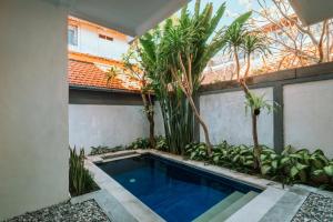 a swimming pool in the middle of a courtyard with trees at Umah Kita in Seminyak