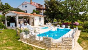 a swimming pool in a yard next to a house at Apartments Ankica - pool & garden in Kampor