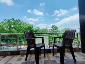 2 Stühle auf einem Balkon mit Blick auf die Bäume in der Unterkunft Hill Top Residency in Sawāi Mādhopur