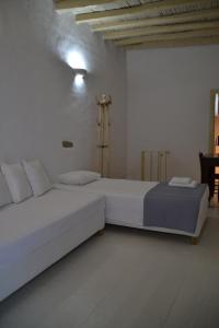 a white bedroom with two beds and a table at Kastro in Parikia