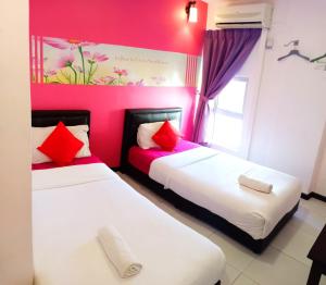 two beds in a room with pink walls at Sweet Memories Hotel in Melaka