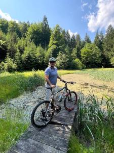 un hombre de pie junto a una bicicleta en un puente en Glamping 4 Acres, en Fryšták