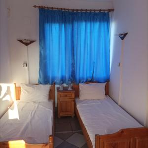 two beds in a room with blue curtains at Къща за гости Бяла Къща in Kavarna +3 photos