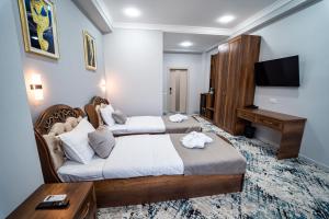 um quarto de hotel com duas camas e uma televisão em Hamilton em Tashkent