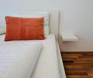 - un oreiller orange sur un lit dans l'établissement A Cozy Flat with Flair surrounded by Nature, à Vienne