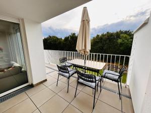 - un balcon avec une table, des chaises et un parasol dans l'établissement A Cozy Flat with Flair surrounded by Nature, à Vienne