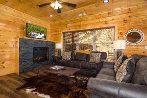 een woonkamer met een bank en een open haard bij Mountain Haven with 2 HotTubs, Thtr &Game Rm, Summer Special,1mi to the Parkway! - Ideal for Family Reunions or Group Getaways! Home away from home in Pigeon Forge