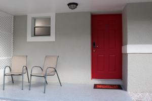 two chairs and a red door on a house at Hidden Ruby-Apartment with Kitchen and Laundry in Lakeland