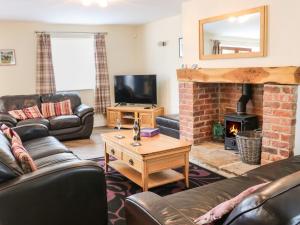 a living room with leather furniture and a fireplace at Stackyard House in Spennymoor
