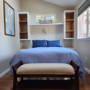 a bedroom with a bed with blue pillows and a bench at Amitabha Wine Country Cottage in Santa Rosa