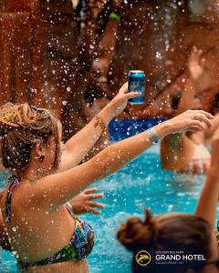 une femme tenant un verre dans une piscine dans l'établissement Suíte Privilegiada no Centro - Golden Dolphin, à Caldas Novas 16 autres photos