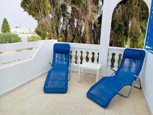 2 sedie blu e un tavolo su un patio di Villa Doudi a Al Ḩārah al Kabīrah