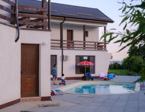 a man standing next to a house with a swimming pool at Agropensiunea Livada lui Cezar și Rares in Kataloi