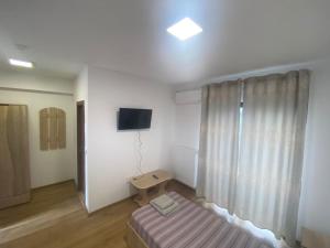 Habitación con cama, TV y ventana. en Agropensiunea Livada lui Cezar și Rares, en Kataloi