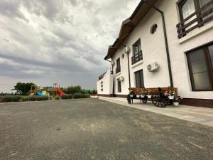 une calèche tirée par des chevaux à côté d'un bâtiment avec une aire de jeux dans l'établissement Agropensiunea Livada lui Cezar și Rares, à Kataloi