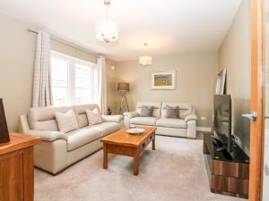 uma sala de estar com um sofá e uma televisão em Glebe Cottage Number 6 em St Andrews