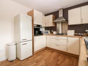 uma cozinha com armários brancos e um frigorífico branco em Glebe Cottage Number 6 em St Andrews