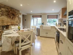 une cuisine avec une table et des chaises et une cuisine avec un mur en pierre dans l'établissement Spinners Cottage, à Stow-on-the-Wold