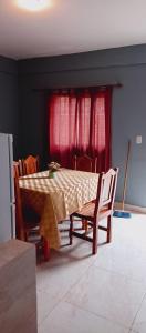 a dining room table and chairs with red curtains at Apartamentos El quincho in El Carmen