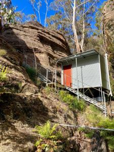 a smallshed on a hill next to a rock at Hatter's Hideout Cave and Lodge in Newnes Junction