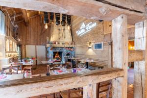 um restaurante com paredes e mesas de madeira e uma lareira em La Vieille Ferme em Manigod