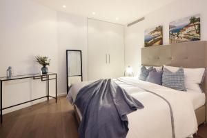 een witte slaapkamer met een groot bed en een spiegel bij SHH - D1 Tower Apartments in Dubai