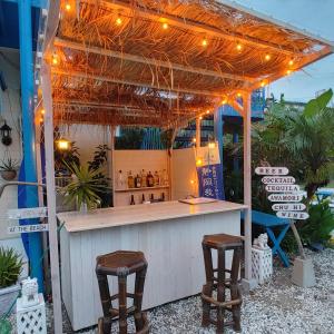 a bar with two stools under a pergola with lights at Guest House Churaumi in Shimoda