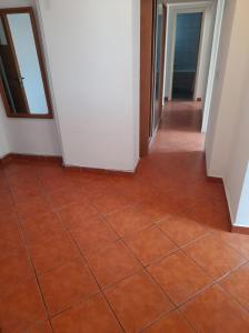 um corredor vazio com piso em azulejo e paredes brancas em 4 rooms apartment downtown Pitesti em Piteşti