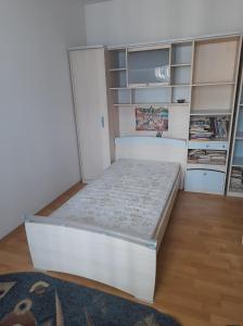 białe łóżko w pokoju z półkami w obiekcie 4 rooms apartment downtown Pitesti w Piteszti