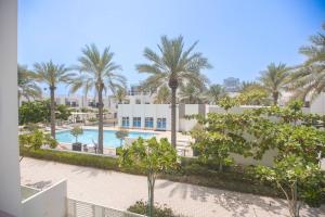 a view of a pool with palm trees and a building at Luxury 3 bdr Villa by the sea 54 in Fujairah