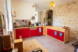 a kitchen with red cabinets and a stone wall at La colonie - Haut Valromey 