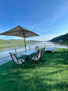 einen Tisch und Stühle mit einem Regenschirm neben dem Wasser in der Unterkunft Casa Anastasia in Dubova