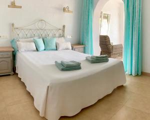 a bedroom with a large white bed with blue curtains at Casa Milana in Moraira +24 photos