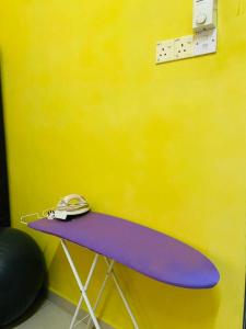 a table with a phone on top of it next to a yellow wall at Homestay Zalida C Musleem in Kampong Alor Gajah
