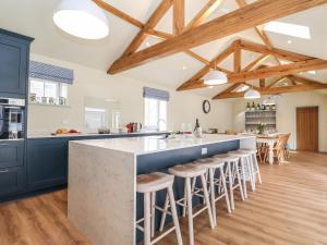 a kitchen with a large island with bar stools at Church Farm Barn in Saxmundham