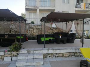 un patio con sombrilla, sillas y mesa en Апартамент с изглед към морето и външен басейн en Balchik