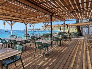 an outdoor restaurant with tables and chairs on a wooden deck at Hotel L'Escale in Porto Pollo