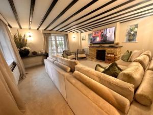 a living room with a large couch and a fireplace at Cotswolds Retreat - Bath & Castle Combe - Hot Tub in Chippenham