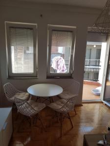 a table and chairs in a room with two windows at Lara apartment in Ohrid