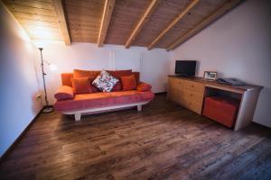 a living room with an orange couch and a television at Wargerhof - Urlaub auf dem Bauernhof in Meltina