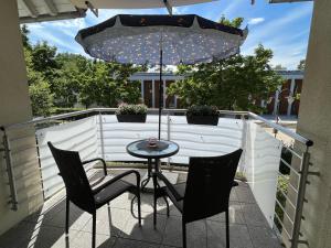 eine Terrasse mit einem Tisch, Stühlen und einem Sonnenschirm in der Unterkunft Ferienwohnungen-Am Kurpark in Bad Saarow