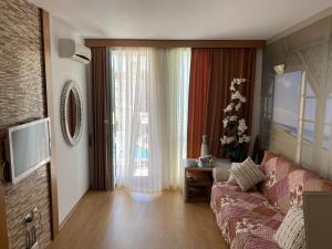 un soggiorno con un divano e una grande finestra di Апартамент на солнечном берегу a Sunny Beach