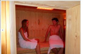 Ein Mann und eine Frau sitzen in einer Sauna in der Unterkunft Chata Drevenica in Habovka