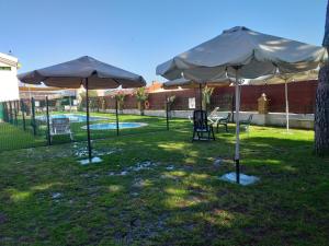 dos sombrillas y una mesa y sillas en un patio en Camping las Catalinas, en Riolobos